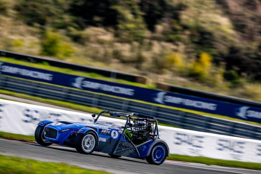 Синий гоночный родстер №1 на фоне баннеров SMP Racing